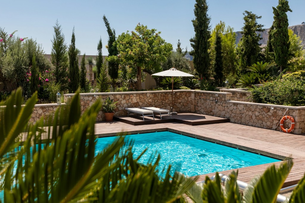 Mediterranean-style swimming pool surrounded by stone walls and greenery