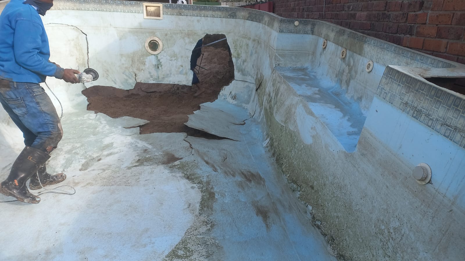 Technicians working on a drained swimming pool shell